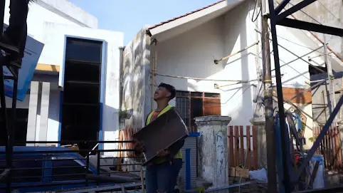 foto mas dony sedang memegang besi penyambung tiang baliho